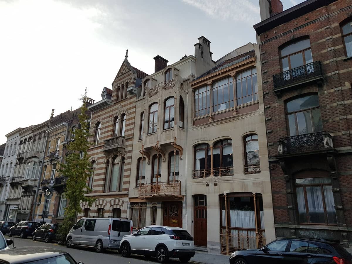 Vista exterior do Museu Horta em Bruxelas, exibindo a ornamentada arquitetura Art Nouveau e grandes janelas em uma rua da cidade.