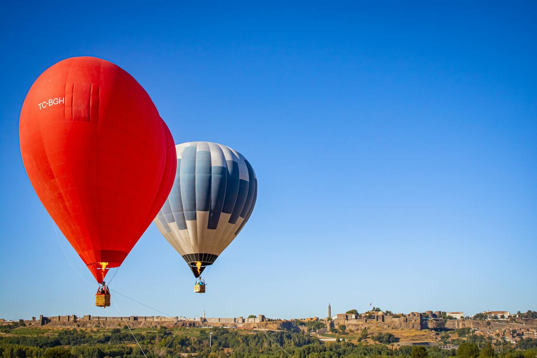 Due mongolfiere colorate che volano su un paesaggio suggestivo con edifici storici e cielo azzurro a Maiorca, perfetto per l'ispirazione di viaggio.