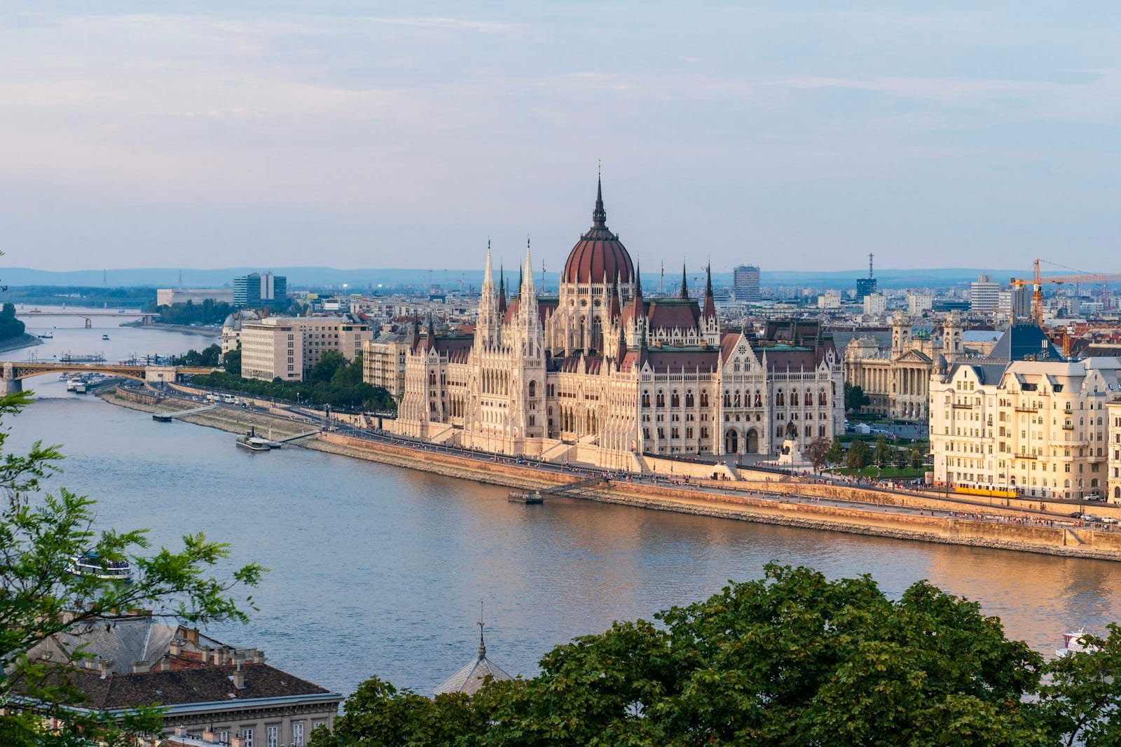 Il Parlamento Ungherese visto dall'altra sponda del Danubio, con le sue iconiche guglie gotiche e il profilo della città in una luce diurna soffusa.