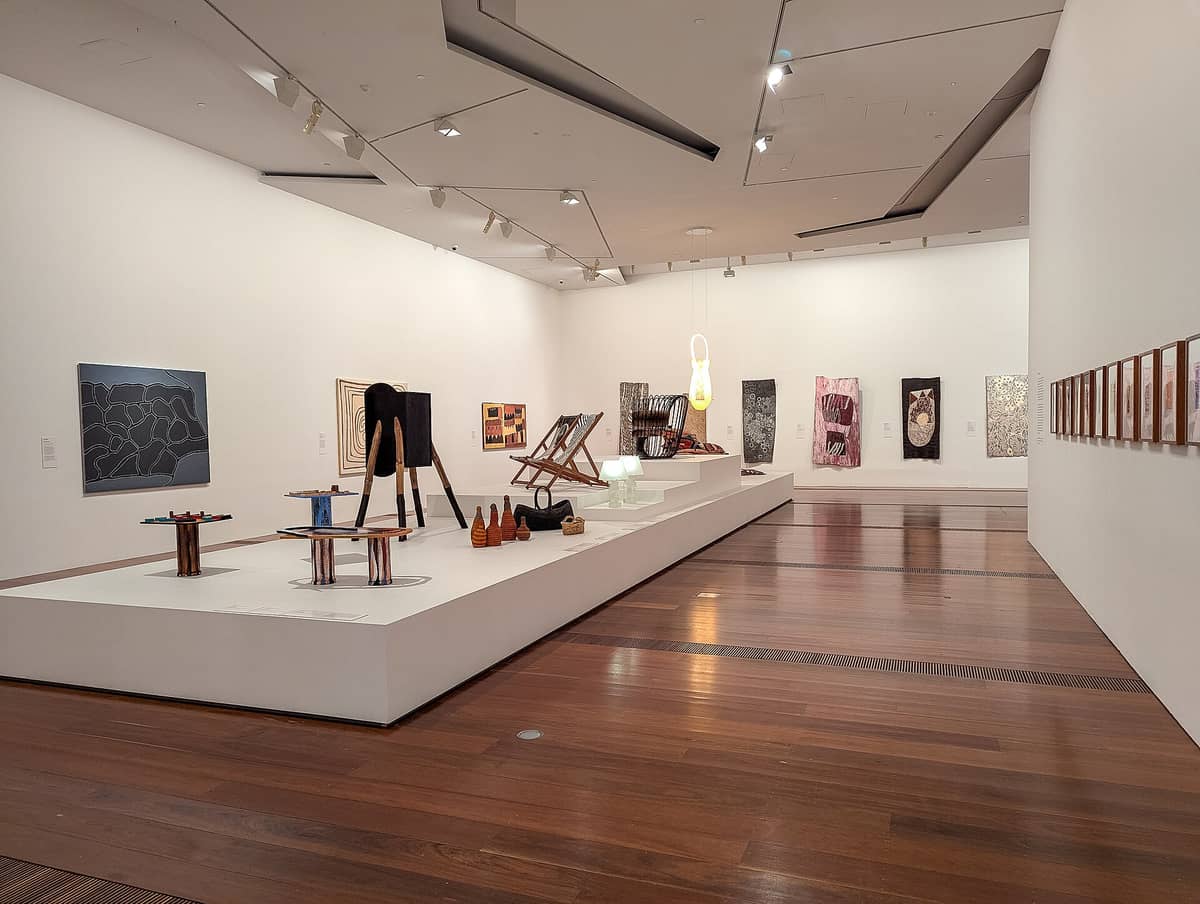 Vista amplia de una sala de exposición contemporánea dentro del Ian Potter Centre: NGV Australia, con obras de arte indígenas y australianas modernas sobre paredes blancas y plataformas de exhibición.