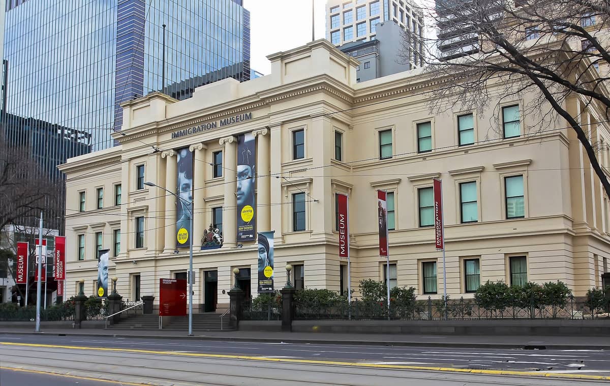 Weitwinkelperspektive des Einwanderungsmuseums Melbourne mit seiner klassischen Fassade, Bannern und Hochhäusern im Hintergrund an der Flinders Street.