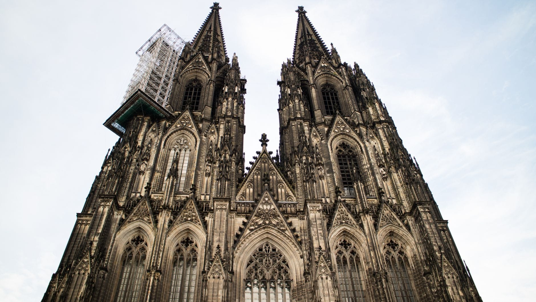ด้านหน้าของมหาวิหาร Cologne Cathedral พร้อมหอคอยสูงสองแห่ง ถ่ายจากด้านหน้าในเวลากลางวันบนท้องฟ้าสว่าง