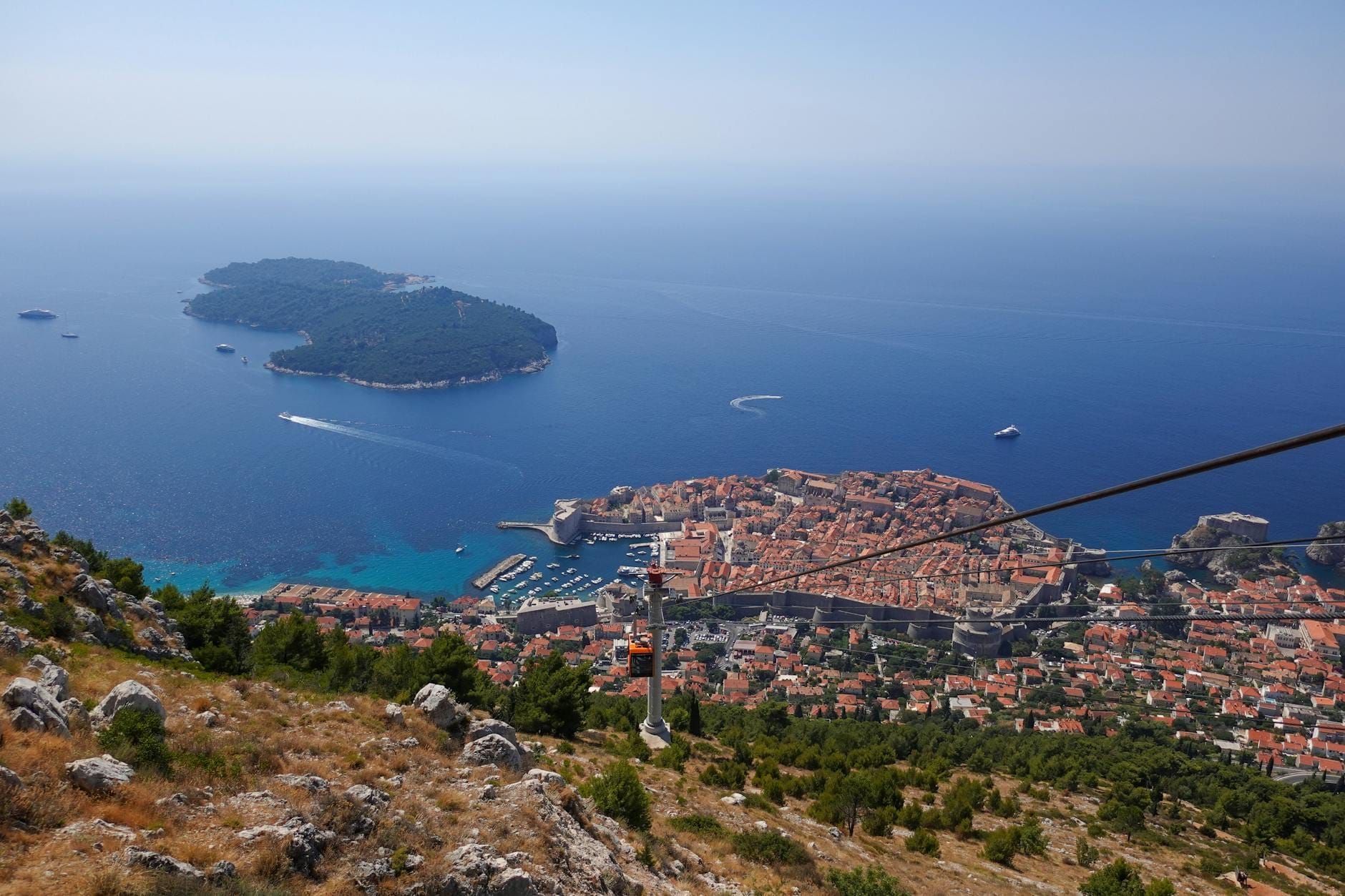 Tầm nhìn từ đỉnh đồi của Phố cổ Dubrovnik, tường thành, cáp treo, bờ biển, đảo Lokrum và biển Adriatic vào một ngày quang đãng.