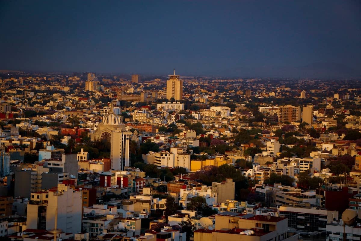 Eine weitläufige Luftaufnahme von Guadalajara, die die städtische Dichte, markante Wahrzeichen und eine weitreichende Stadtlandschaft im dramatischen Abendlicht zeigt.