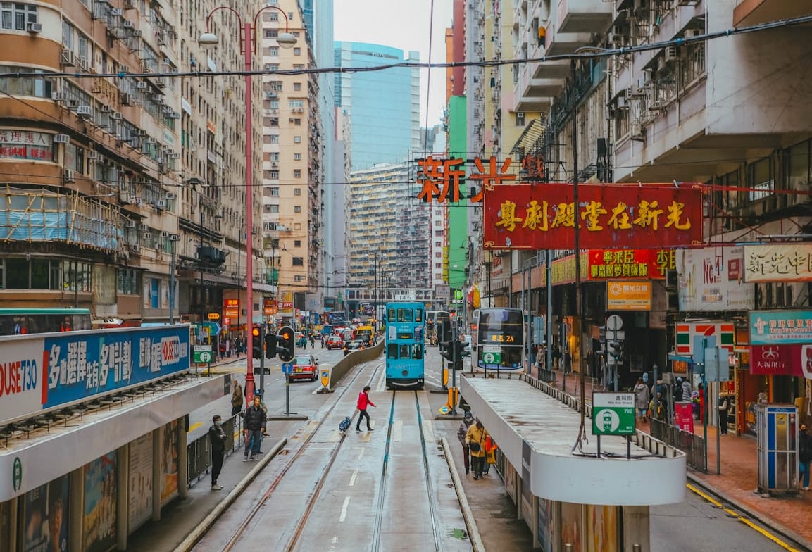 Rua em Hong Kong com bonde de dois andares, prédios densos e lojas locais