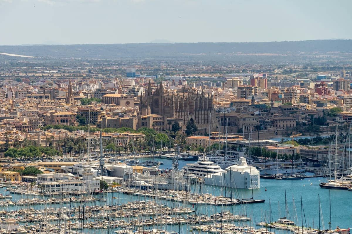 Vista ampla de Palma de Mallorca mostrando a cidade, o porto cheio de barcos e a icônica catedral no centro.
