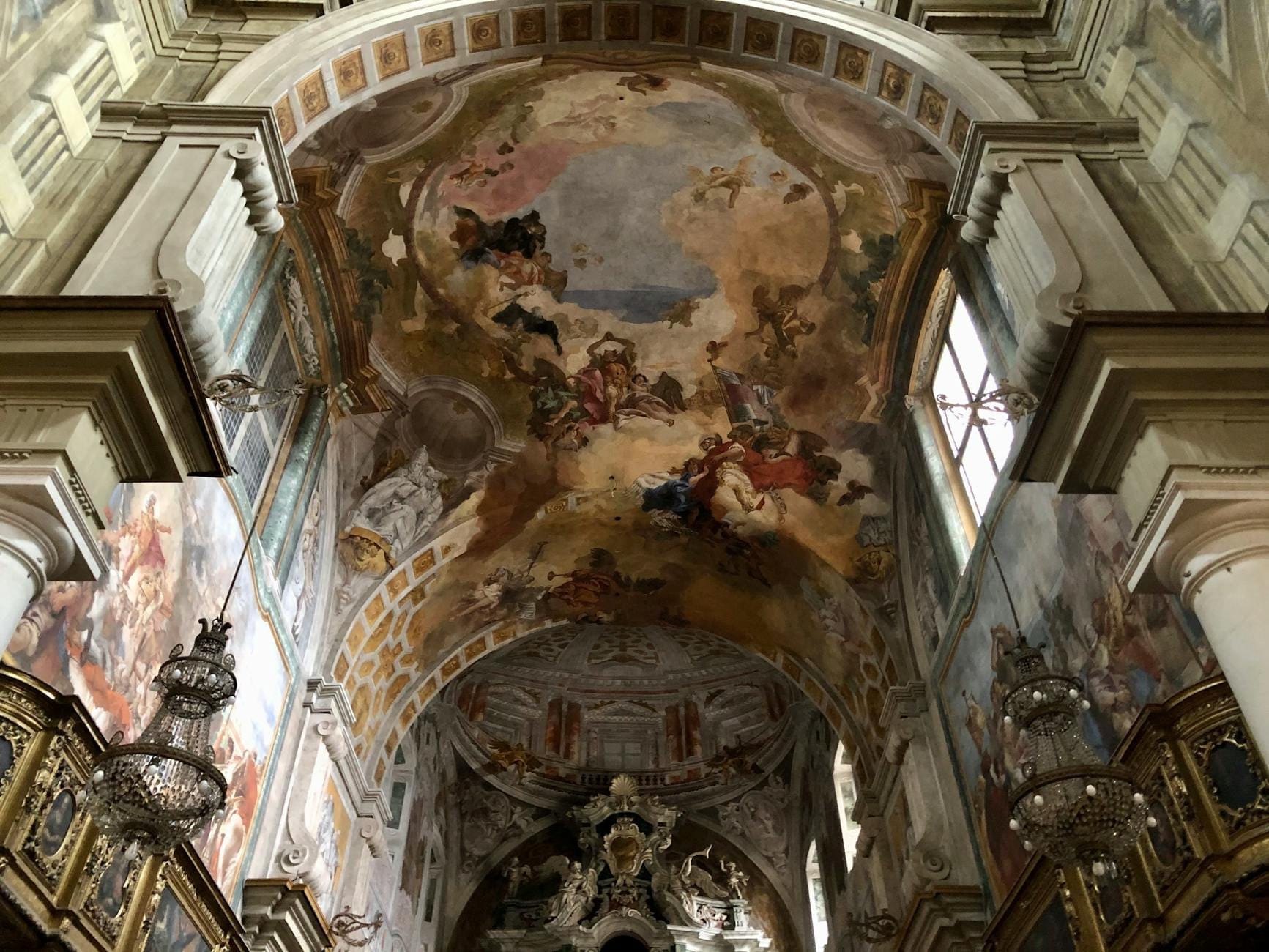 Vue intérieure d'une église historique richement décorée à Naples, avec de superbes fresques, des lustres et des arcs détaillés.