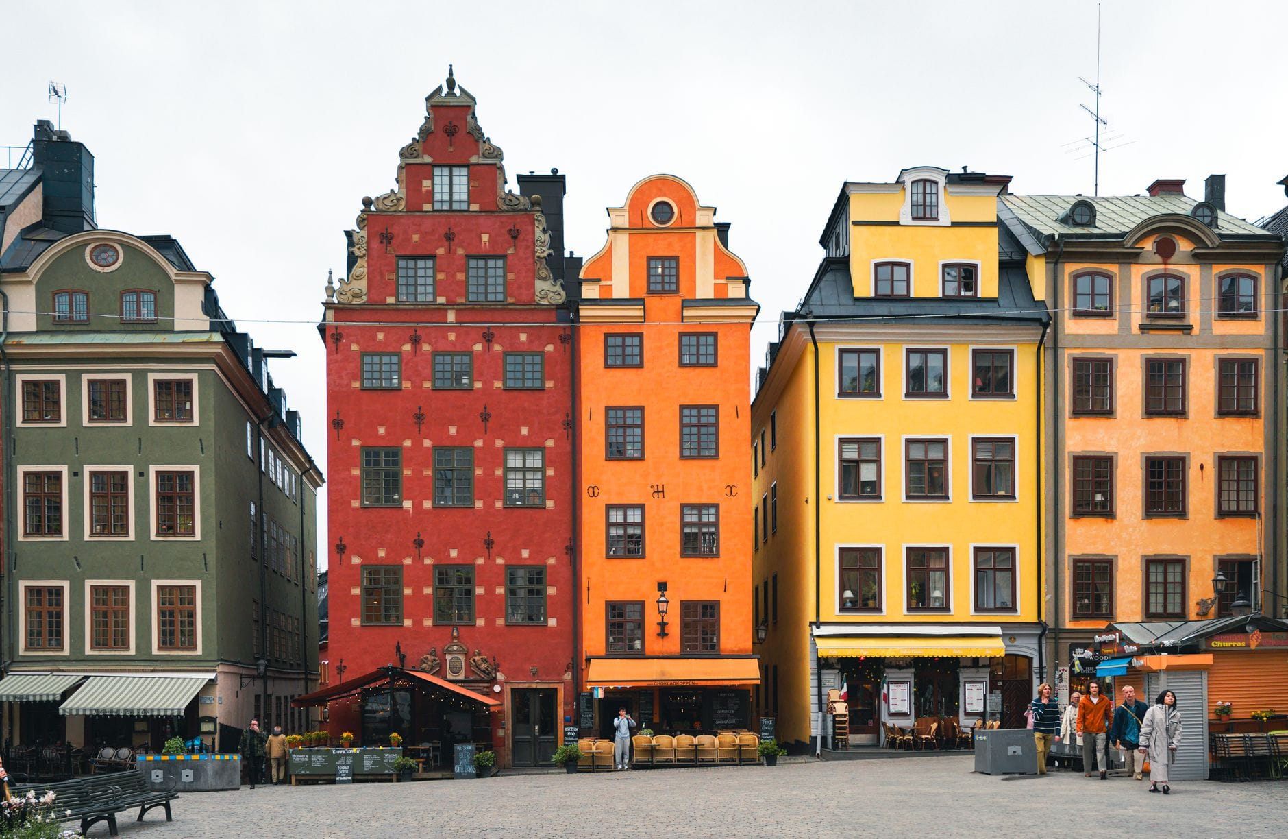 วิวของจัตุรัส Stortorget ใน Gamla Stan กรุงสตอกโฮล์ม พร้อมอาคารประวัติศาสตร์สีสันสดใสอันเป็นสัญลักษณ์และผู้คนที่เดินอยู่ในลาน