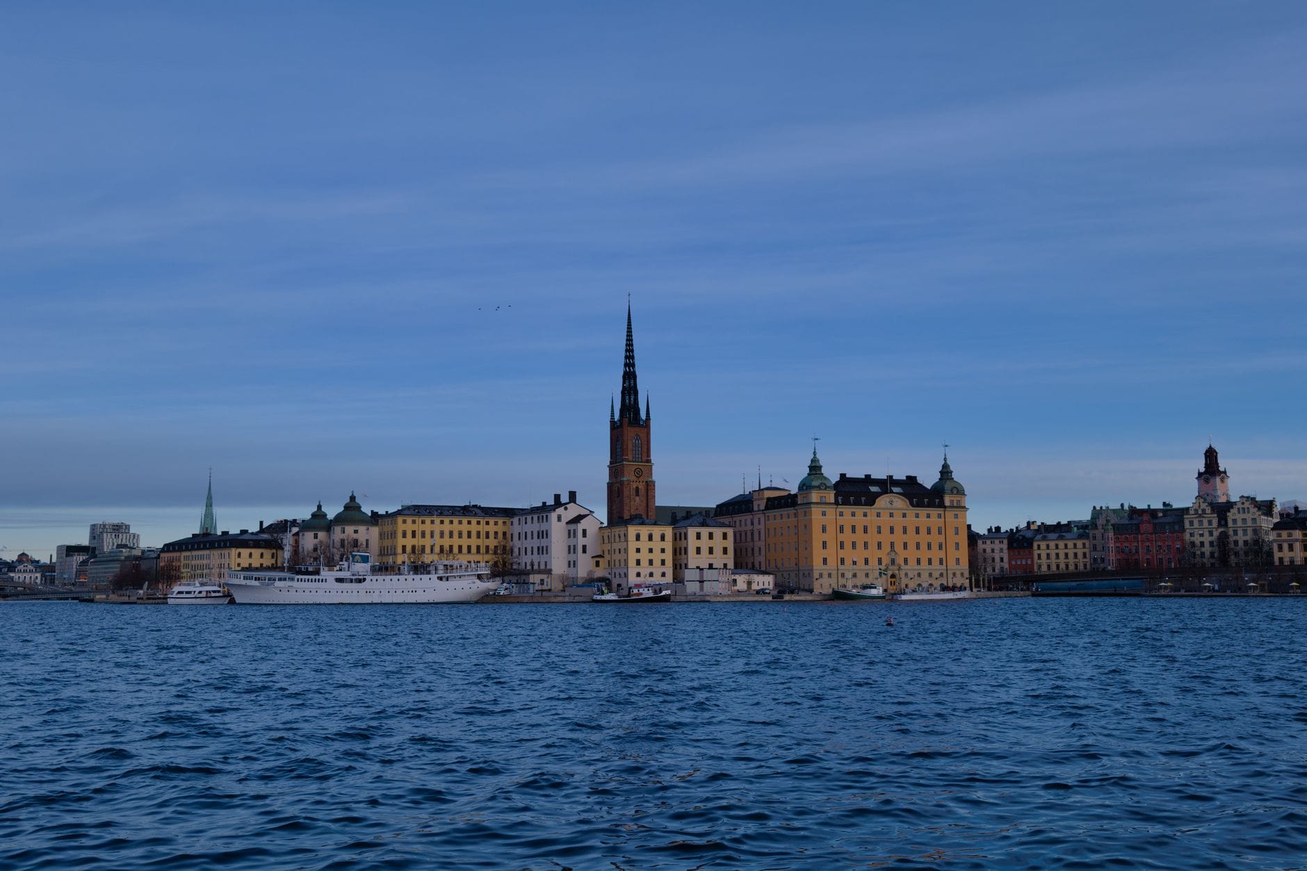 วิวริมน้ำย่านกลางสตอกโฮล์ม อาคารประวัติศาสตร์ เห็นยอดโบสถ์และเกาะ Riddarholmen ภายใต้ท้องฟ้าสีคราม