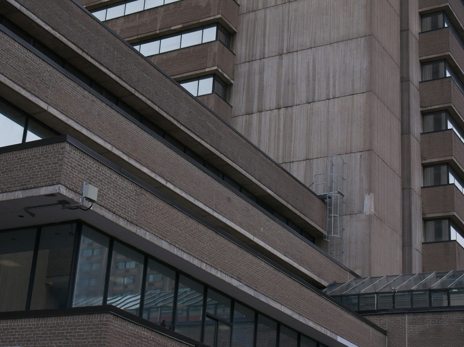 Vista aproximada de um hospital moderno ou instalação médica em Toronto, com grandes janelas e estrutura de vários andares sob luz natural.