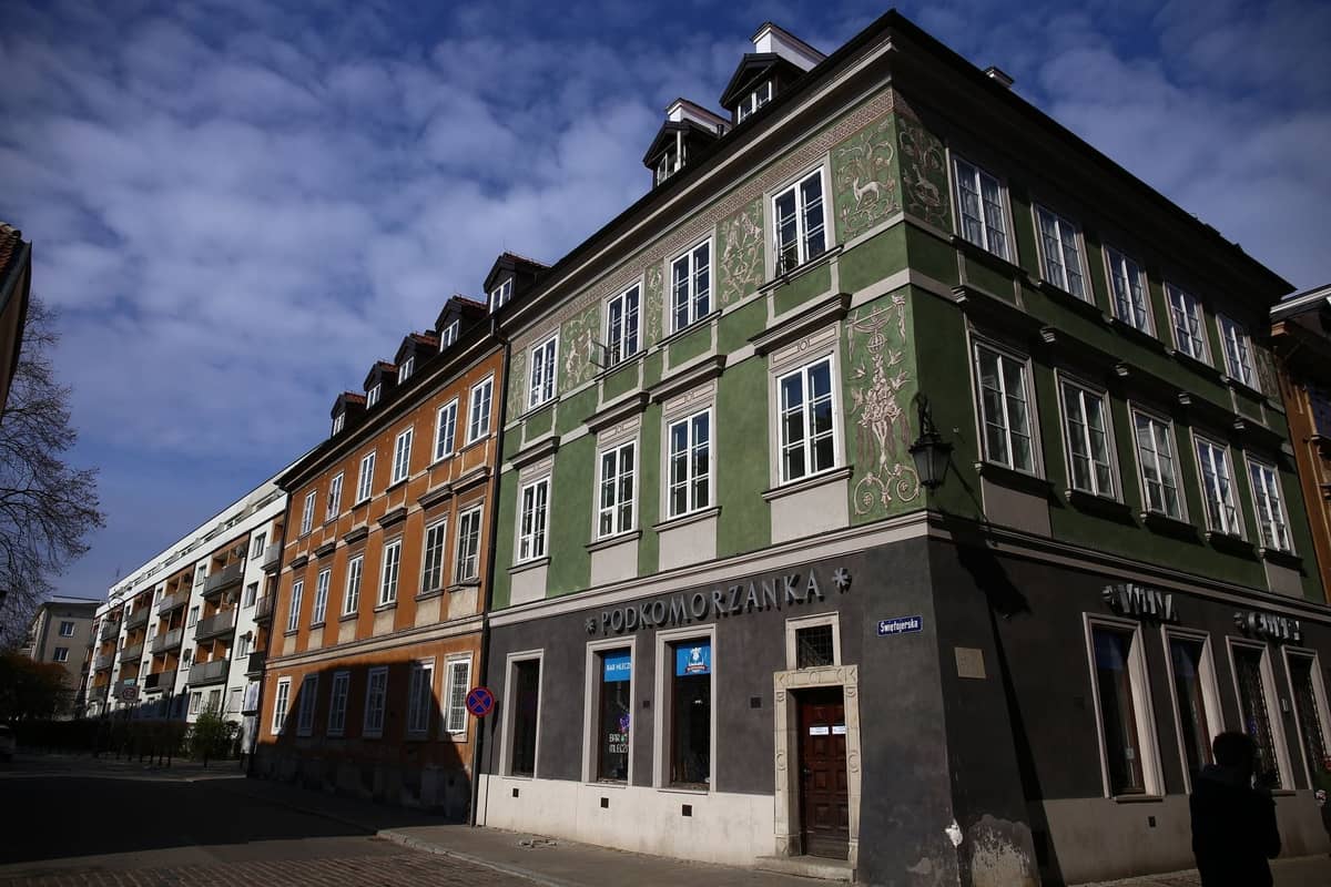 Un coin de rue à Varsovie avec des immeubles d'appartements colorés et historiques sous un ciel bleu, mettant en valeur le caractère local en dehors du centre de la Vieille Ville.