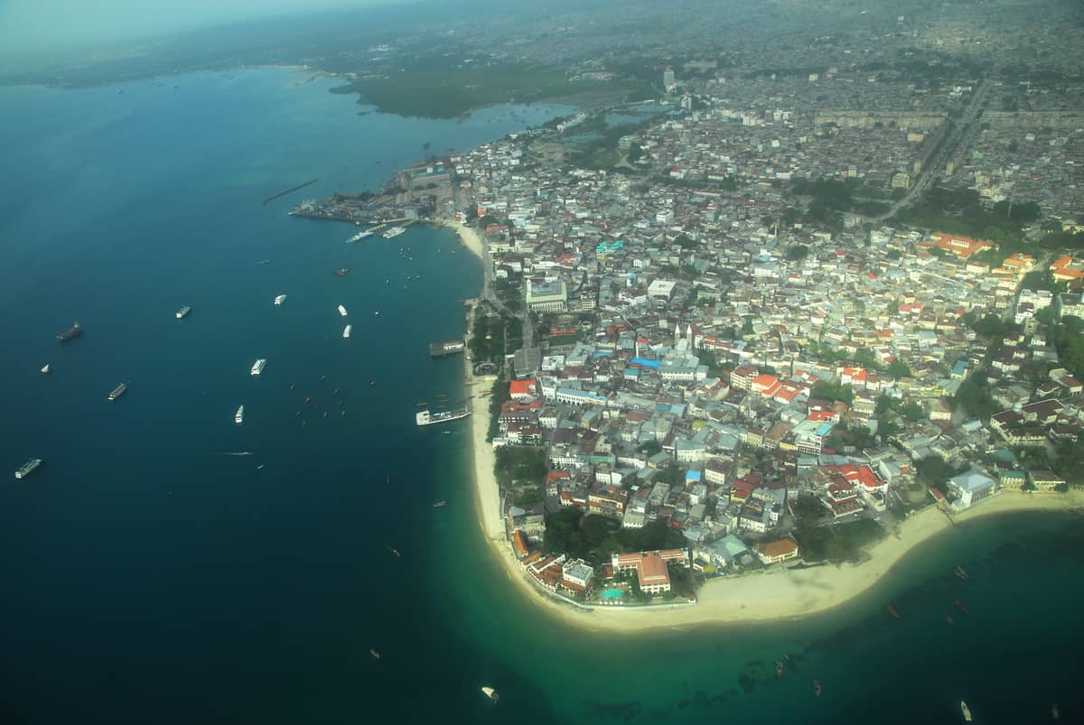 Vista aerea di Stone Town e della costa di Unguja, l'isola principale di Zanzibar, che mostra il mix di area urbana, spiagge e porto.