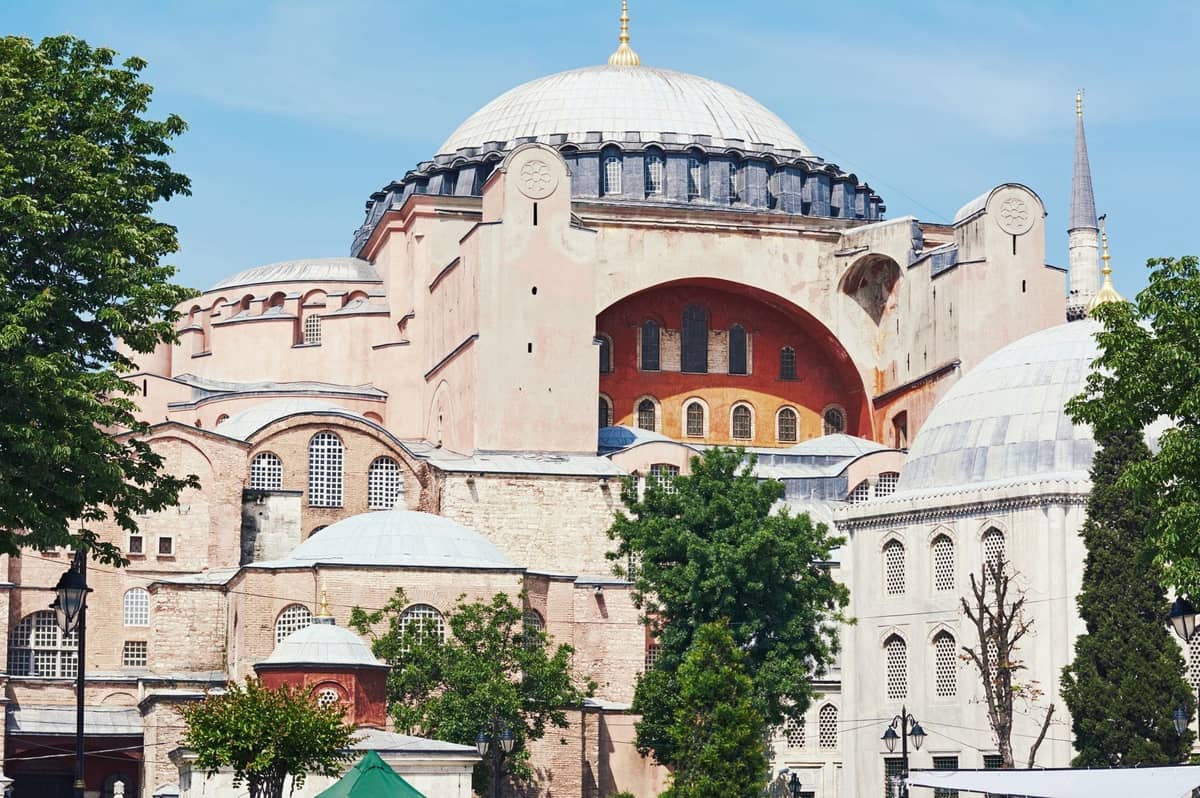 Вид снаружи на Hagia Sophia в Стамбуле: большой купол, минареты и историческая архитектура в солнечный день.