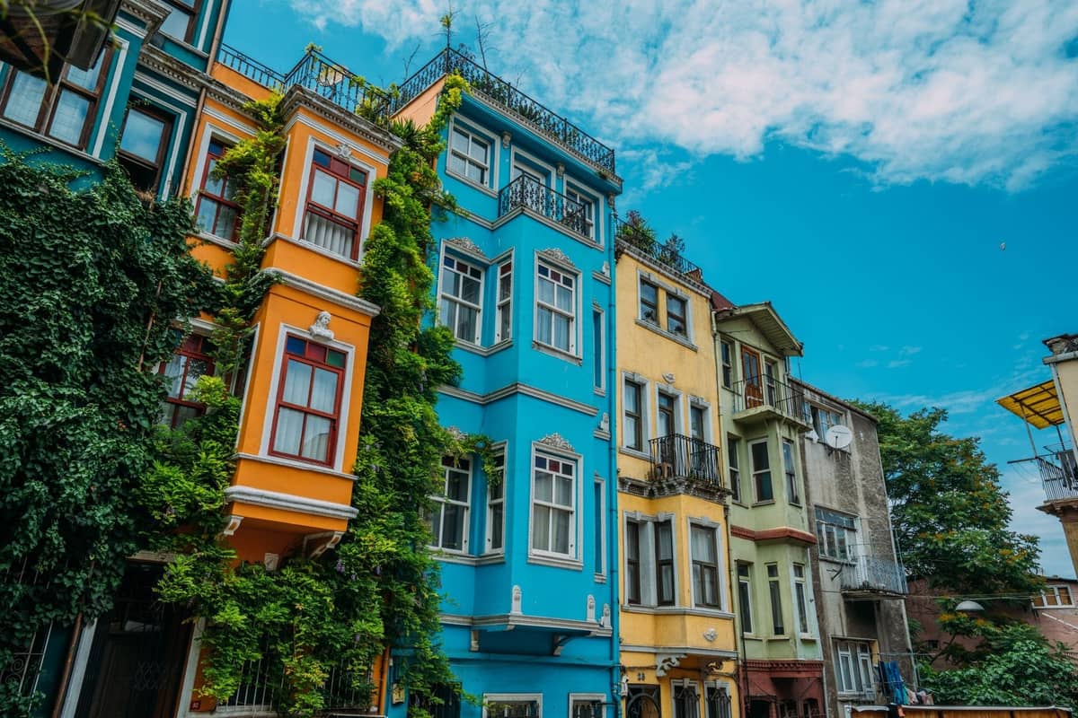 Bunte historische Apartmentgebäude in einem lebhaften Istanbuler Viertel unter einem strahlend blauen Himmel, die ein Gefühl lokaler und günstiger Unterkunftsmöglichkeiten vermitteln.