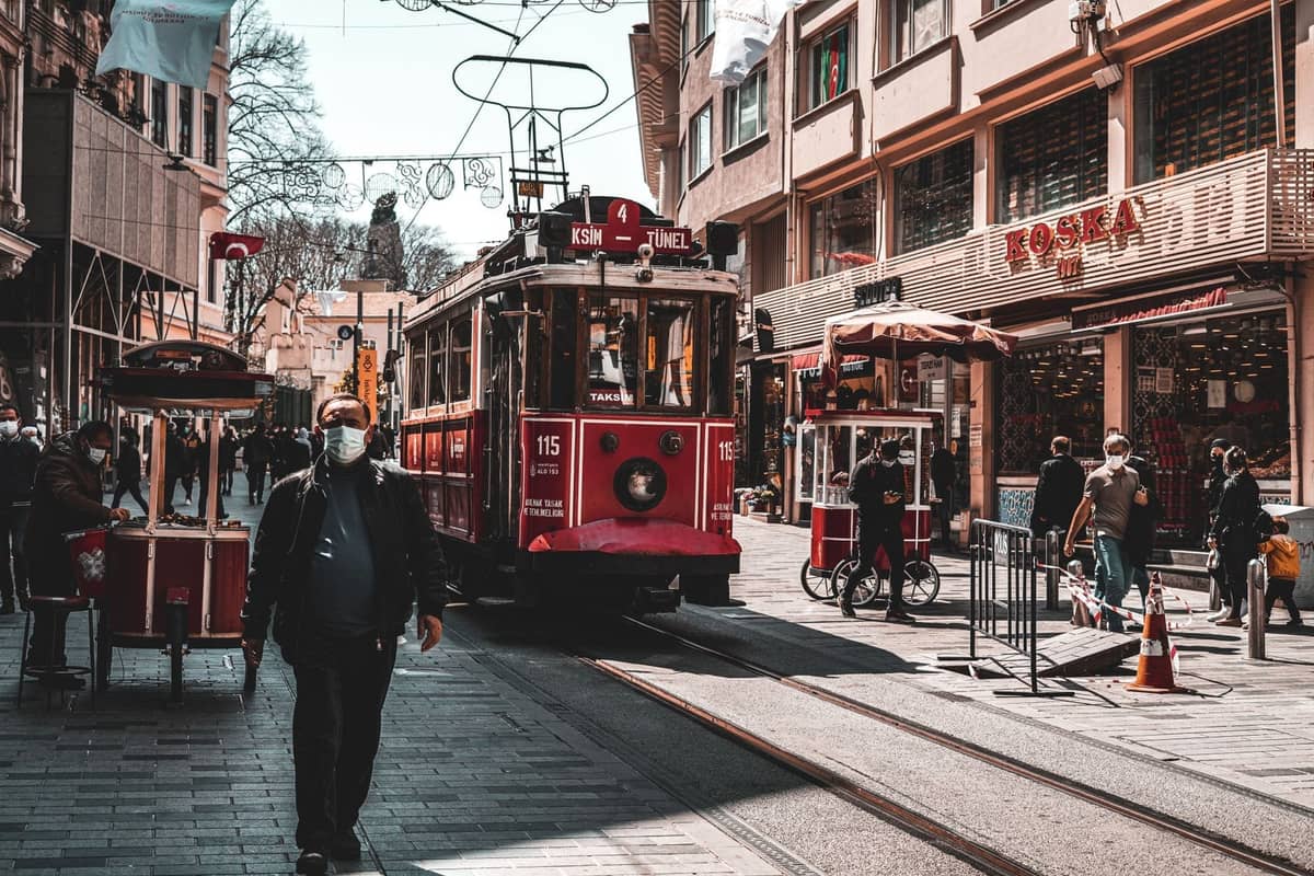 Ruchliwa ulica w Stambule z czerwonym tramwajem, straganami z jedzeniem i ludźmi spacerującymi w ciągu dnia.