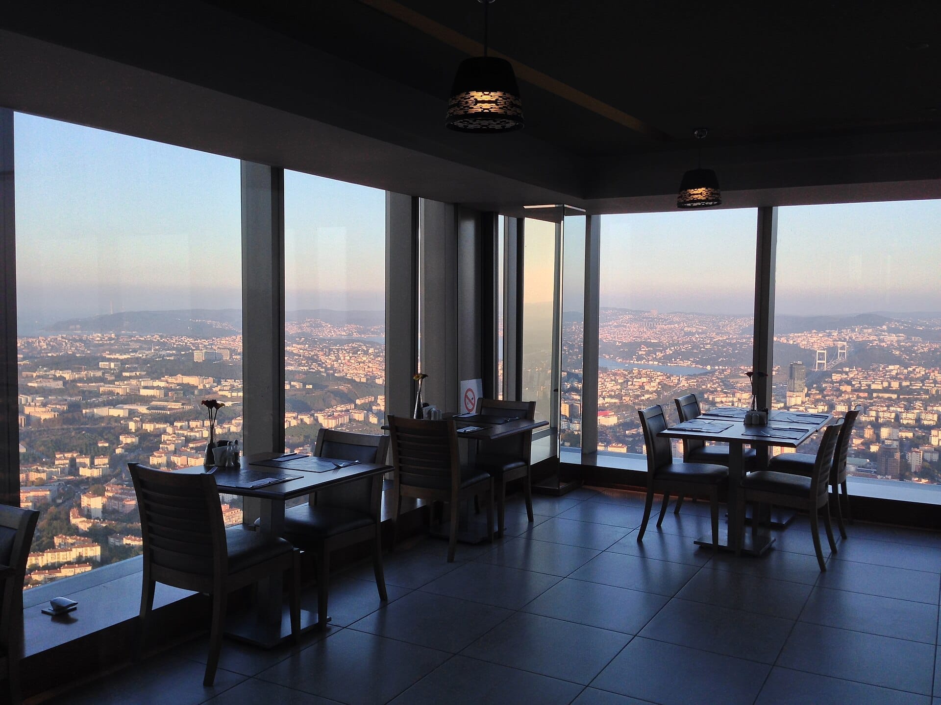 Ampia area di seduta interna all'Istanbul Sapphire Observation Deck con grandi finestre che rivelano ampie vedute dello skyline urbano di Istanbul e del Bosphorus Bridge.