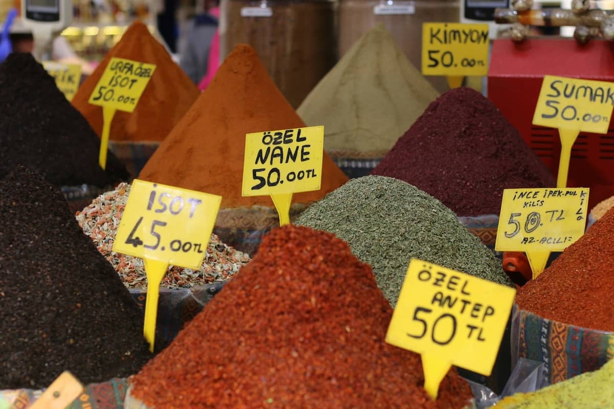Montones coloridos de especias con letreros en turco en un animado puesto del mercado de Estambul, evocando la cultura local de la comida callejera.