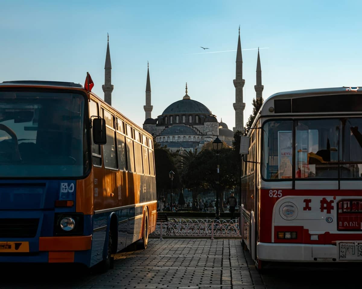 Zwei geparkte Busse mit der Hagia Sophia und ihren Minaretten im Hintergrund bei Tageslicht in Istanbul.