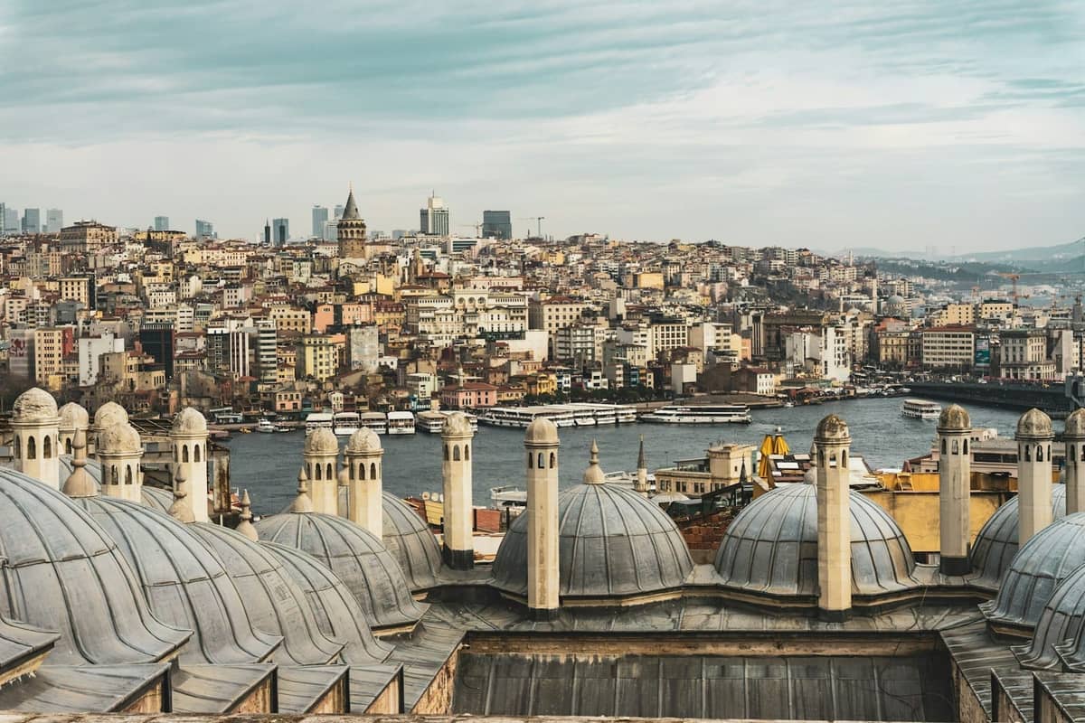 Mehrere Kuppeldächer von Moscheen mit einem Panoramablick auf Istanbul und den Bosporus im Hintergrund.