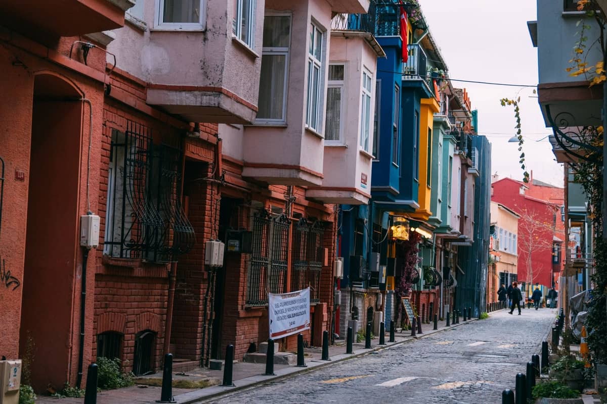 Kolorowe domy z epoki osmańskiej na urokliwej ulicy w dzielnicy Fener i Balat w Stambule, z ludźmi spacerującymi po brukowanej drodze.