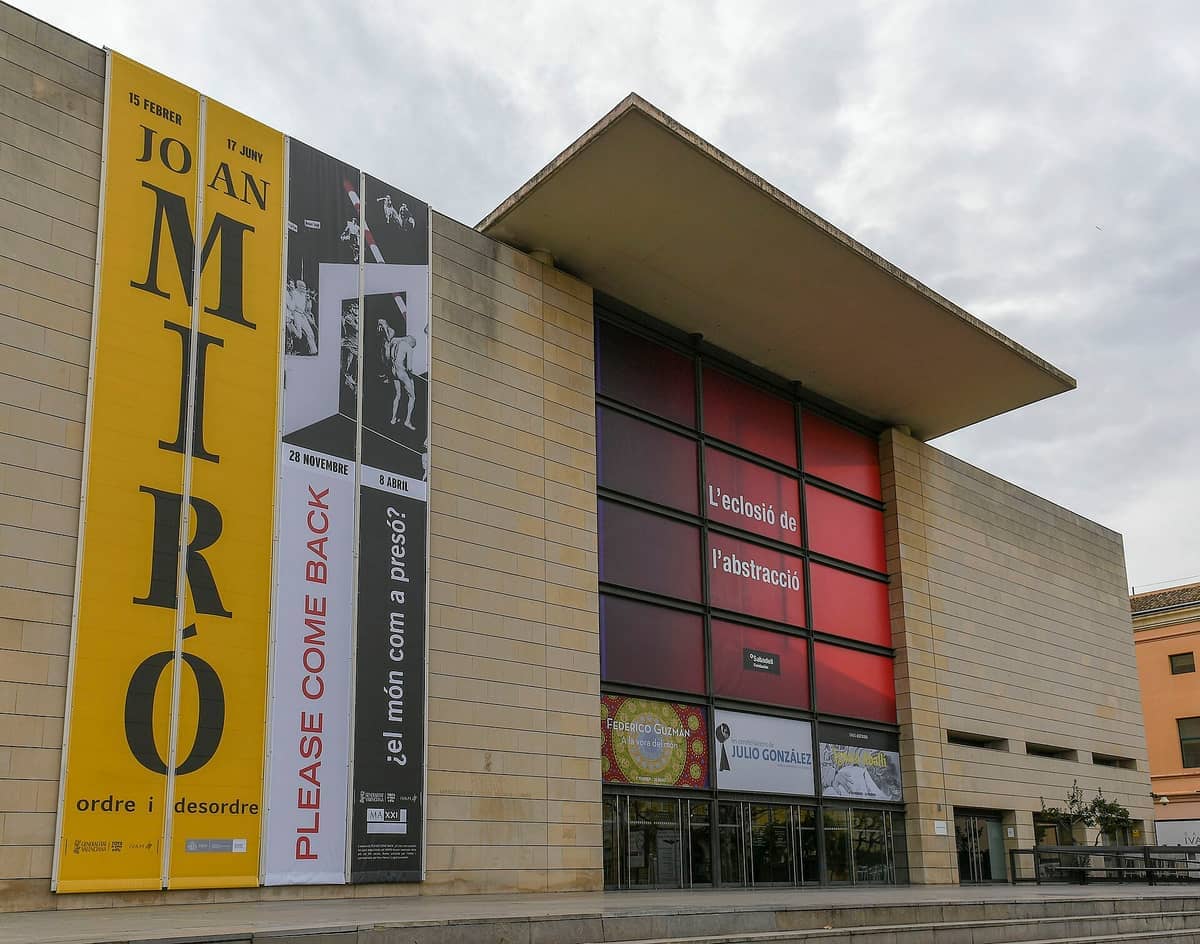 La moderna facciata in cemento dell'IVAM a Valencia, con grandi striscioni per le mostre d'arte in corso sotto un cielo nuvoloso.