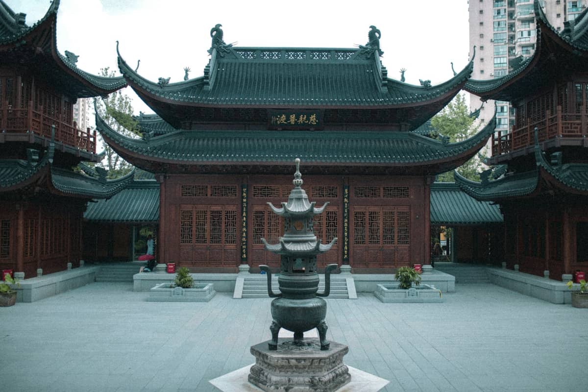Innenhof des Jade-Buddha-Tempels in Shanghai mit traditionellen Gebäuden mit geschwungenen Dächern und einem großen Räuchergefäß in der Mitte.