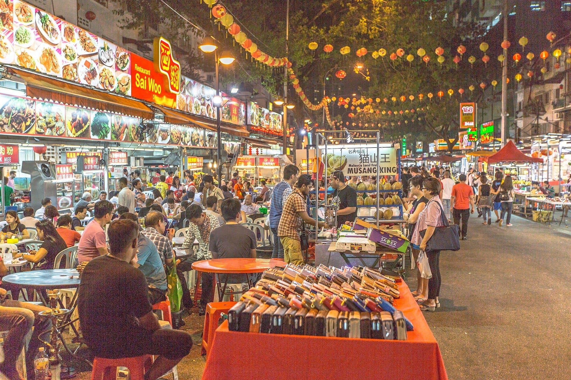 Crowds gather at outdoor tables under glowing lanterns along Jalan Alor, a vibrant food street in Kuala Lumpur full of bustling eateries.