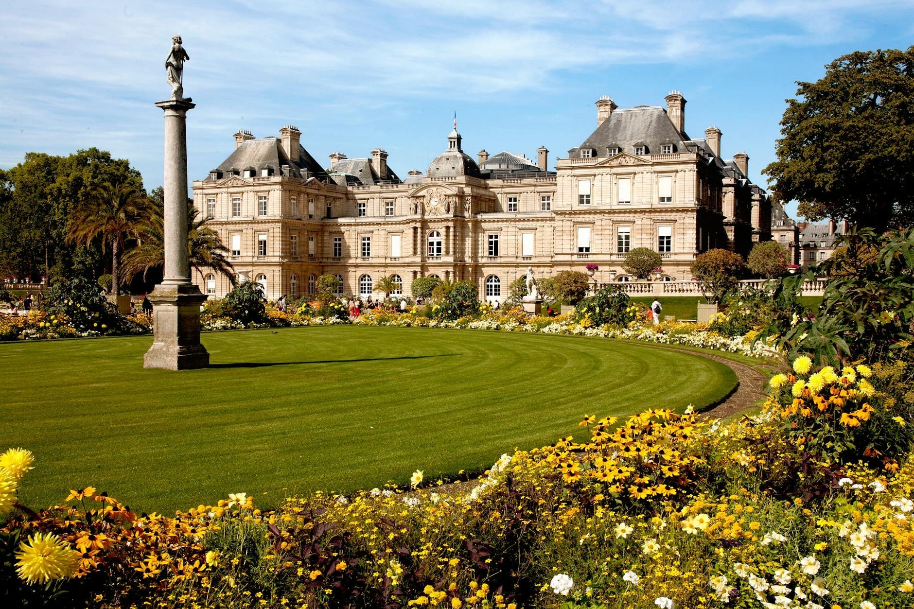 Il maestoso Palazzo del Lussemburgo si staglia oltre aiuole geometriche dai colori vivaci, prati ben curati e una statua slanciata sotto un cielo azzurro intenso nel Jardin du Luxembourg.