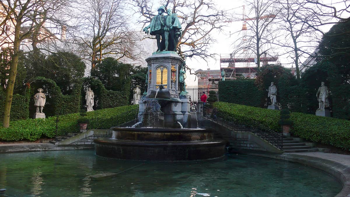 Fonte com estátuas dos Condes de Egmont e de Hoorne rodeada de vegetação exuberante e figuras esculpidas no Jardin du Petit Sablon, em Bruxelas.