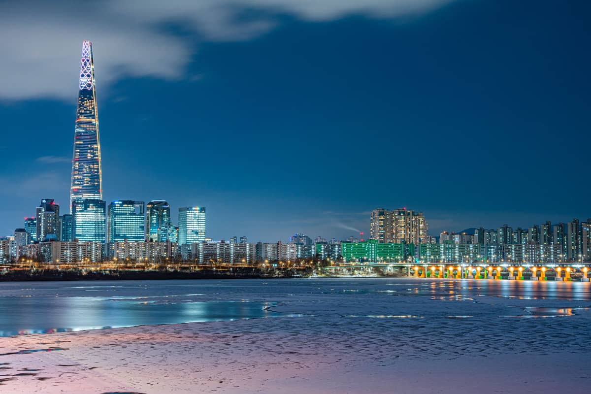 Vista noturna do horizonte de Seul com a Lotte World Tower e o rio Han parcialmente congelado em primeiro plano