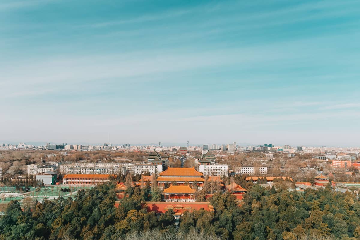 Weites Panorama vom Gipfel des Jingshan-Parks mit Blick über die Verbotene Stadt und ihre symmetrische Anlage mit Peking im Hintergrund.