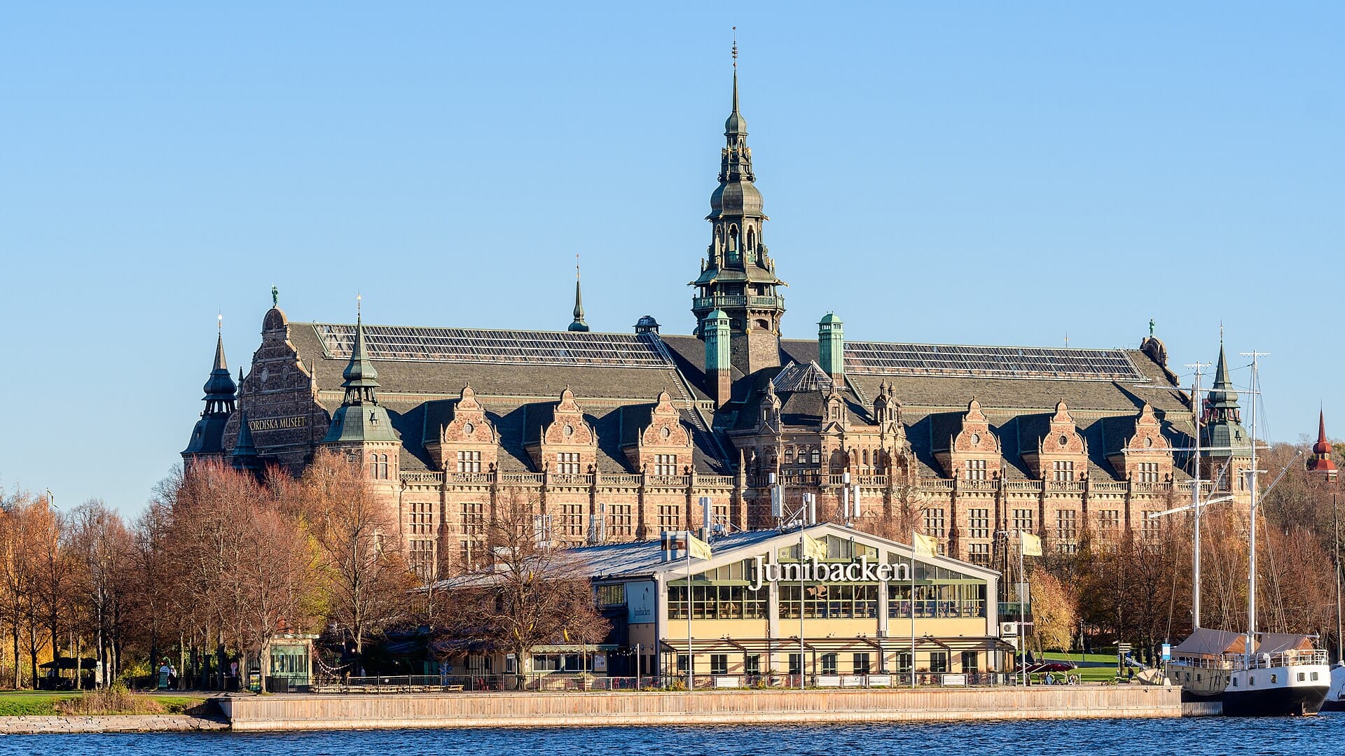 ภาพมุมกว้างพิพิธภัณฑ์เด็ก Junibacken บนเกาะ Djurgården ในสตอกโฮล์ม ด้านหลังเป็นพิพิธภัณฑ์ Nordiska Museet โดดเด่นและท้องฟ้าสีฟ้าสดใส