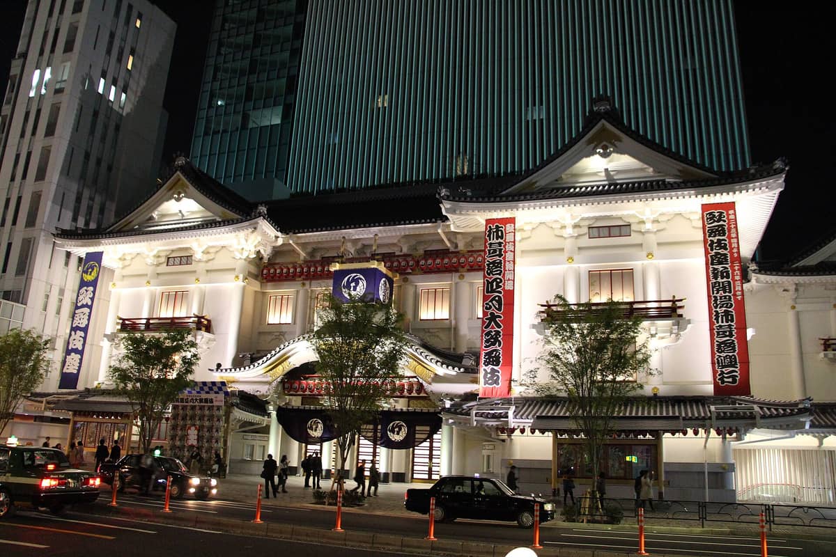 Kabukiza Theatre at night in Ginza, Tokyo, brightly illuminated with its neo-baroque facade, traditional lanterns, and modern skyscrapers in the background.