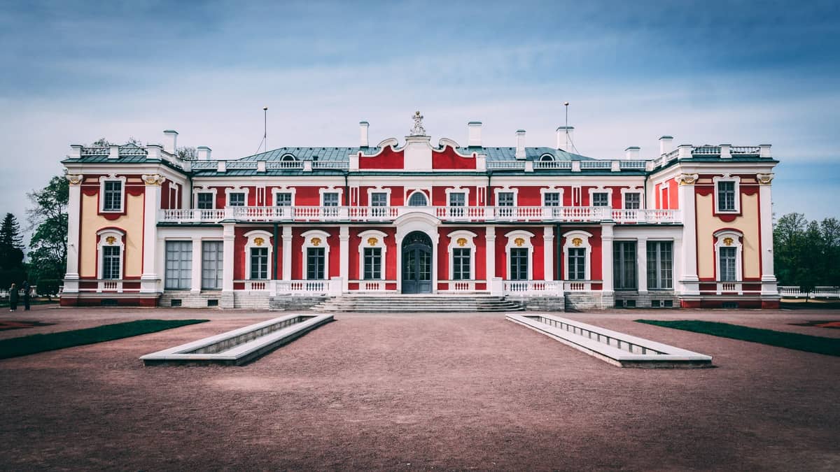 Frontansicht von Schloss Kadriorg in Tallinn, Estland, mit seiner rot-weißen Barockfassade und symmetrischen Gestaltung an einem bewölkten Tag.