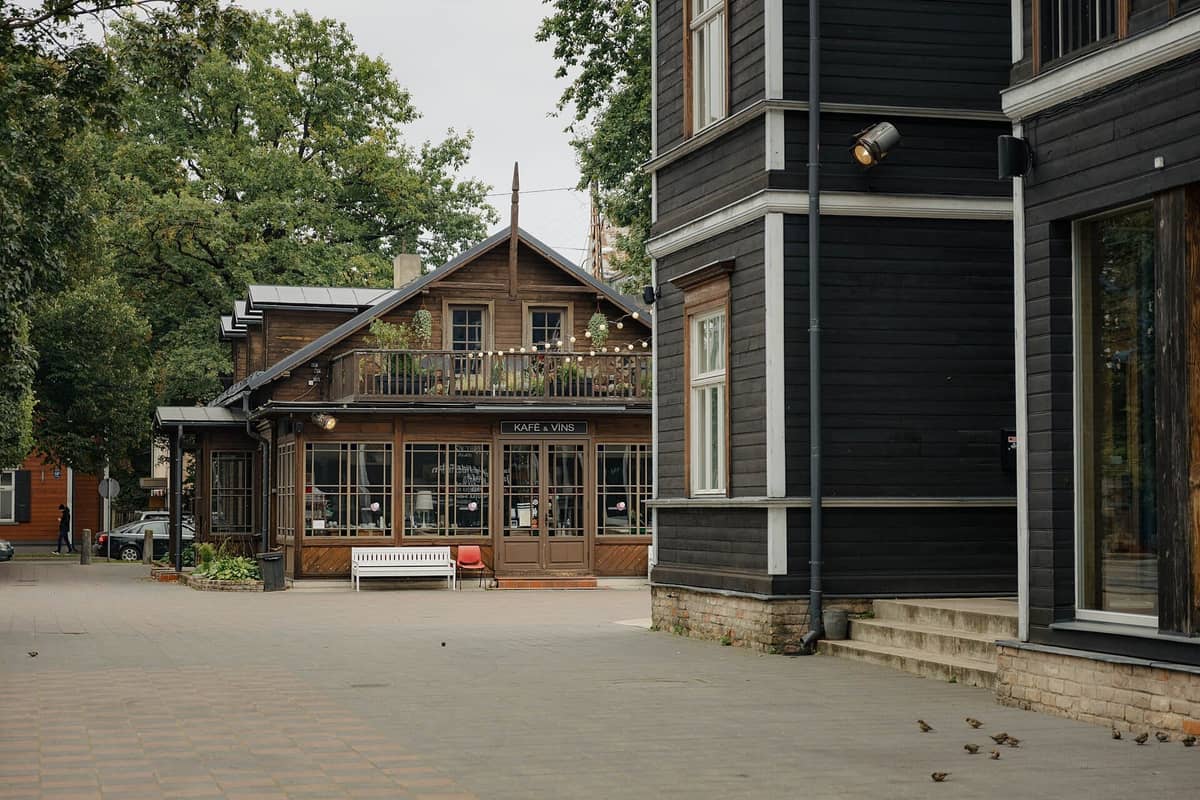 Restaurierte Holzbauten des Kalnciema Quarters in Riga mit einem gemütlichen Café und umgebenden Grünflächen in einer fußgängerfreundlichen Umgebung.