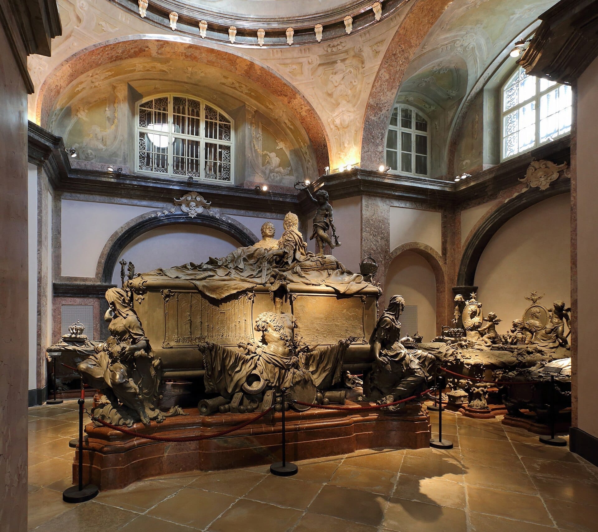 Barocke Sarkophage mit aufwendigen Skulpturen stehen unter gewölbten Decken in der Kapuzinergruft, der Kaisergruft Wiens.