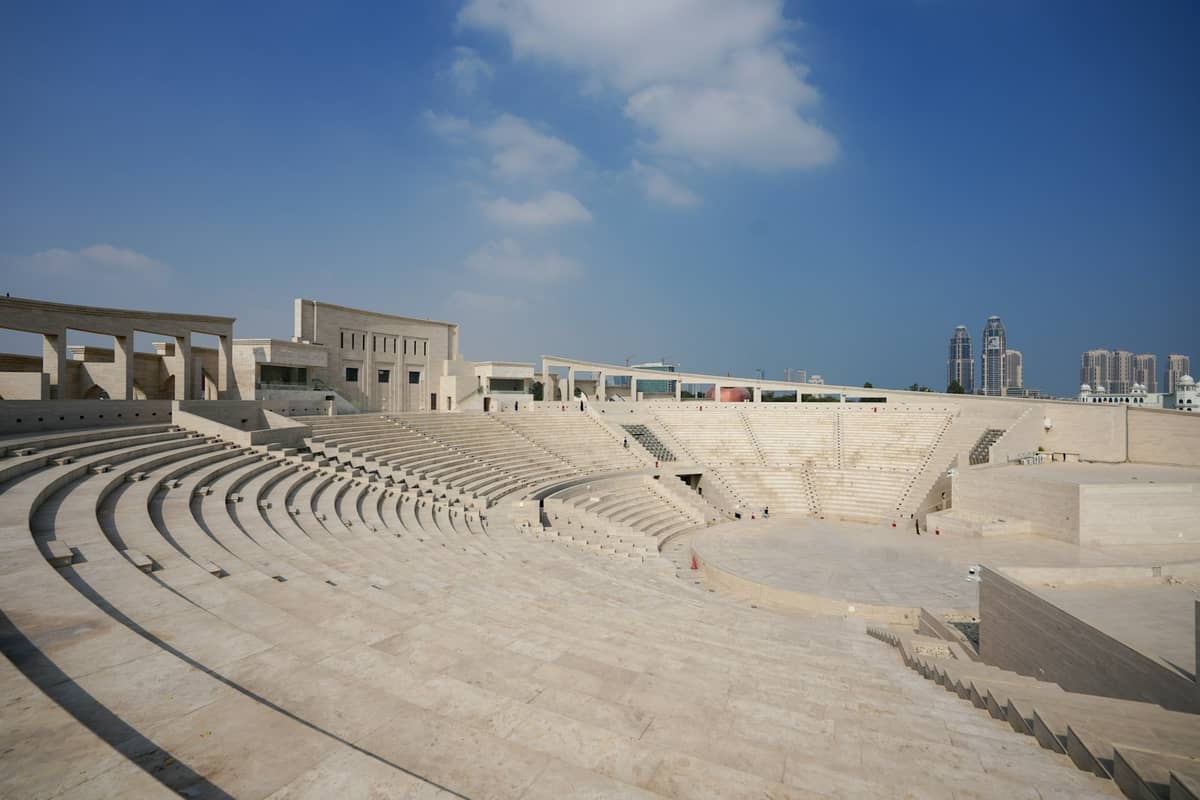 Weitwinkelaufnahme des Katara Amphitheaters mit Marmorrängen und Bühne unter blauem Himmel – klassisch-griechische Designelemente in Doha, Katar.