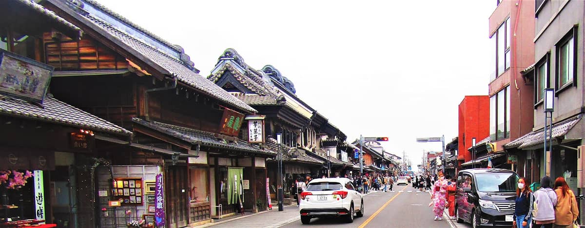 Street view of Kawagoe’s main warehouse district in Little Edo with traditional Edo-period buildings, tiled roofs, and people walking along the busy road.