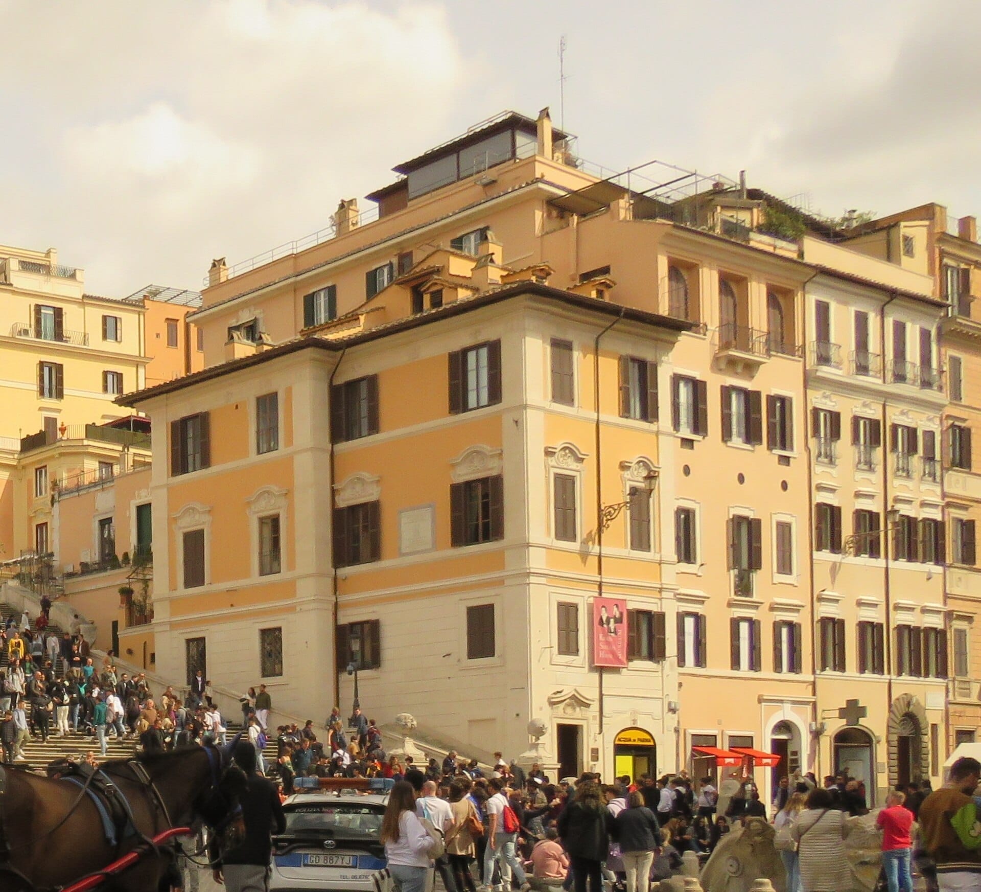 The Keats-Shelley House in Rome, a peach-pink historic building at the base of the Spanish Steps, surrounded by visitors on a sunny day.