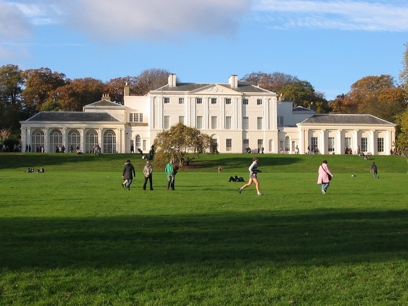 Kenwood House si trova sotto un cielo azzurro, circondata da lussureggianti prati verdi e visitatori che passeggiano e si rilassano a Hampstead Heath.