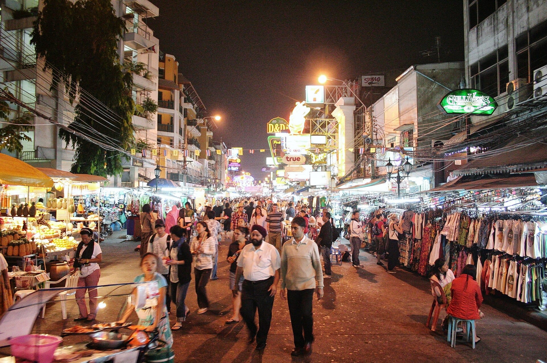 Khao San Road a Bangkok di notte con mercato di strada, folla di persone e negozi illuminati al neon