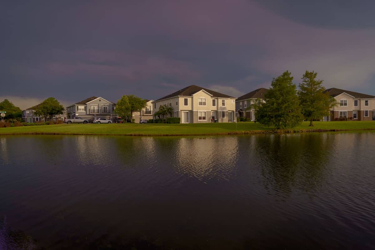 Suburban vacation homes with manicured lawns and a pond under an overcast sky in Kissimmee, Florida.