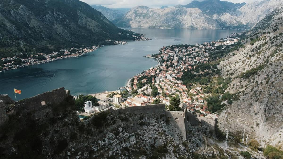 A panoramic view from Kotor fortress walls showing the zigzagging path up the mountain, the old town below, and the Bay of Kotor.