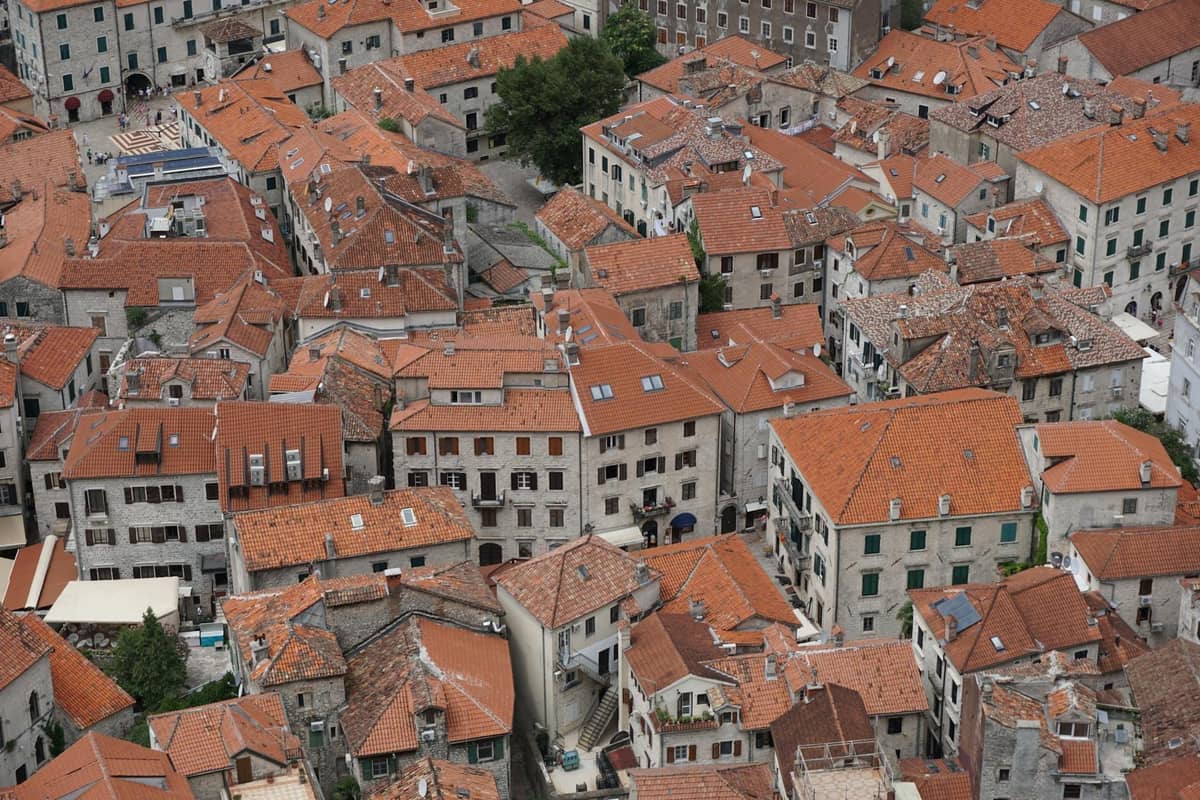Aerial view of Kotor old town with red-tiled rooftops and narrow historic buildings, seen from an elevated viewpoint.