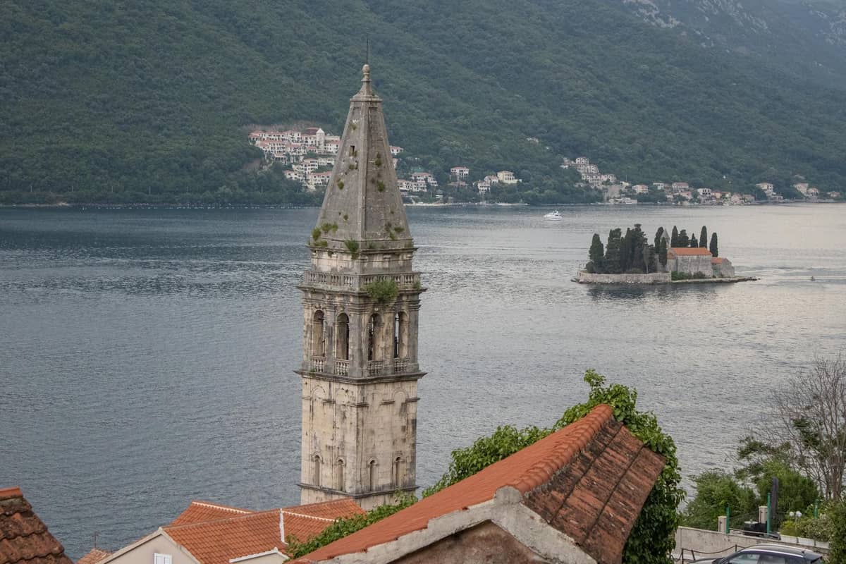 View of Perast bell tower with one of the Bay of Kotor’s famous island churches in the water behind.