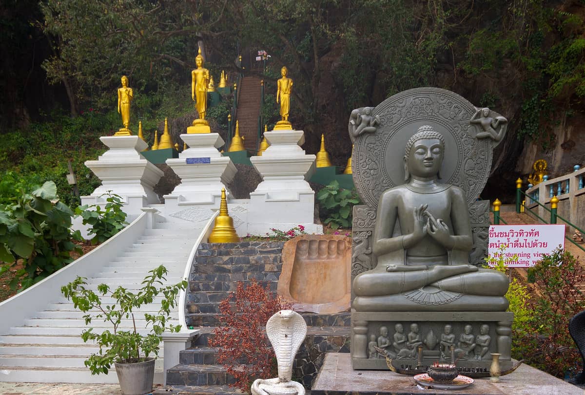 Estátuas budistas e uma escadaria que leva à caverna de calcário no Wat Tham Sua, um templo proeminente em Krabi Town, Tailândia.