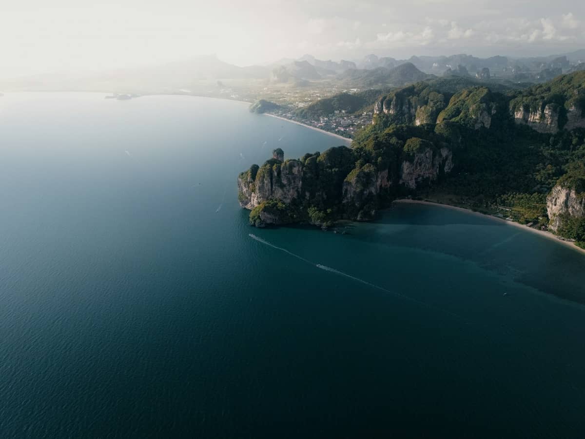 Vue aérienne de la côte de Krabi avec la plage d'Ao Nang, ses impressionnantes falaises calcaires et sa végétation luxuriante dominant la mer d'Andaman au lever ou au coucher du soleil.
