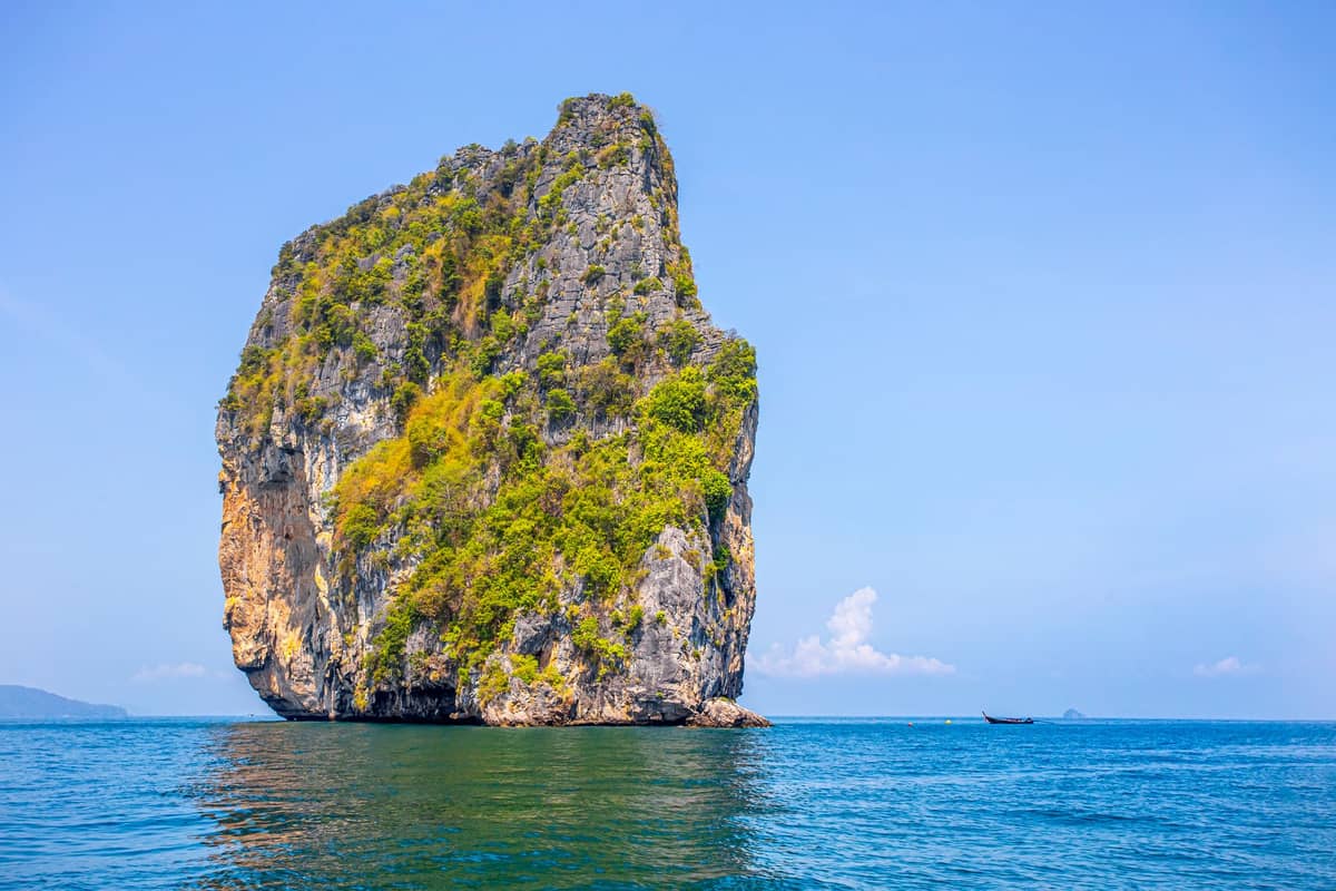 Große Kalksteinkarst-Insel, die an einem hellen, klaren Tag steil aus dem Meer der Provinz Krabi, Thailand, aufragt – vom Wasser aus fotografiert.