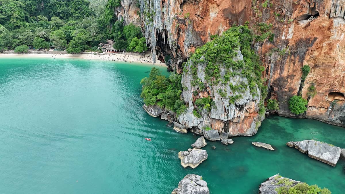Vista aérea de aguas turquesas, imponentes acantilados de piedra caliza, frondoso bosque y una playa en Krabi, Tailandia, que muestran por qué la zona es ideal para el kayak.