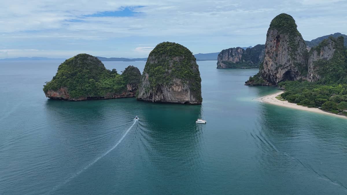 Luftaufnahme dramatischer Kalksteininseln, blaugrünem Meer, Strand und üppiger grüner Küste in der Nähe von Krabi, Thailand, an einem klaren Tag.